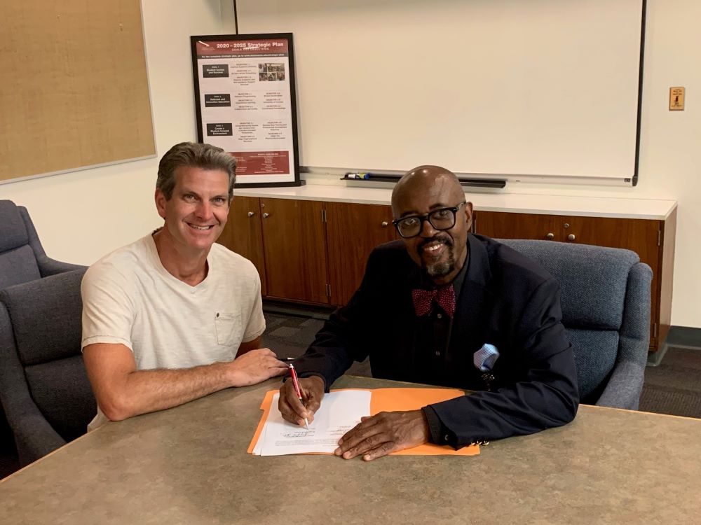 Mark Bergmooser and Dr. Kojo Quartey sign faculty contract.