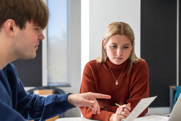 Two students reviewing a paper