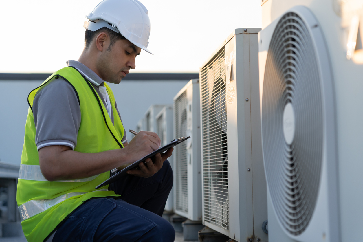 Man performing energy audit looking at AC units