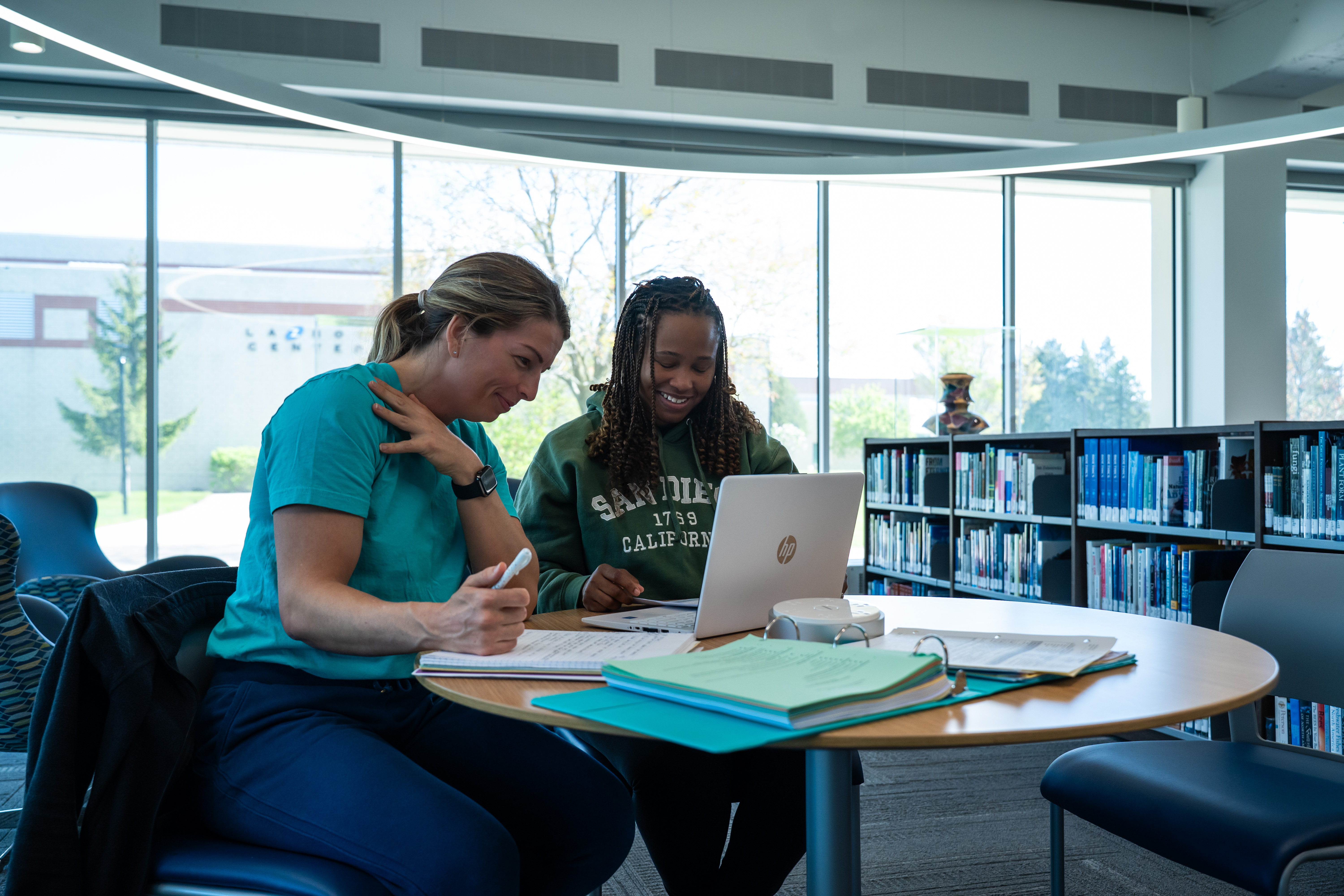 students doing work in library together on laptop