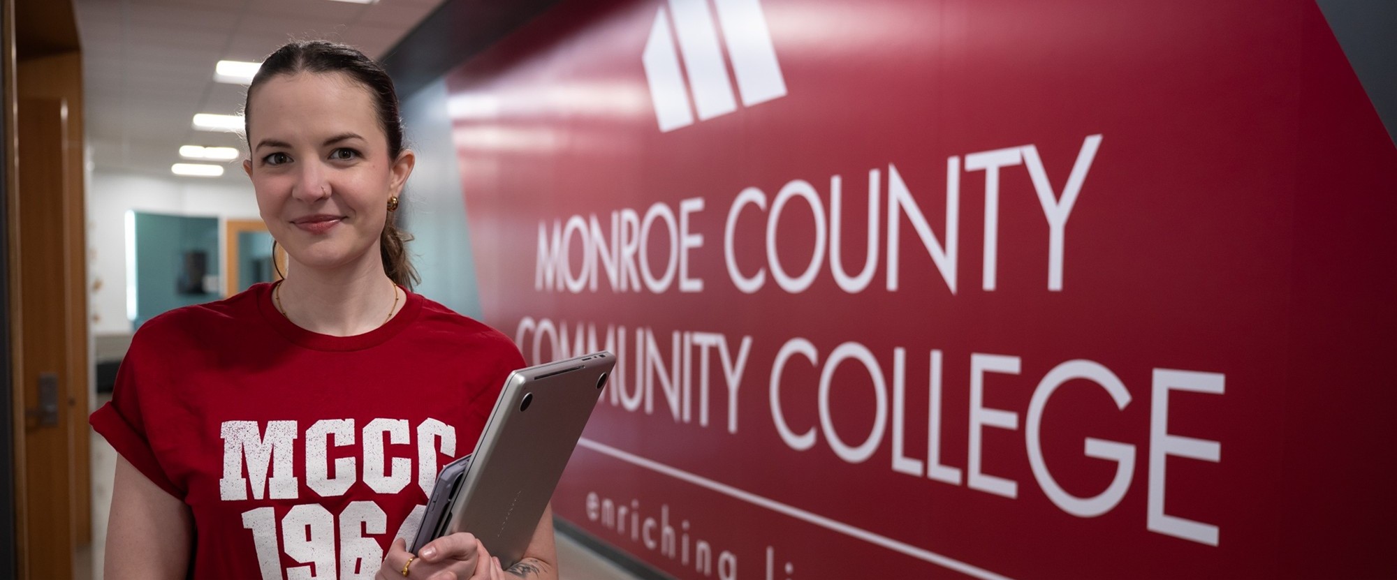 Student next to MCCC logo on wall