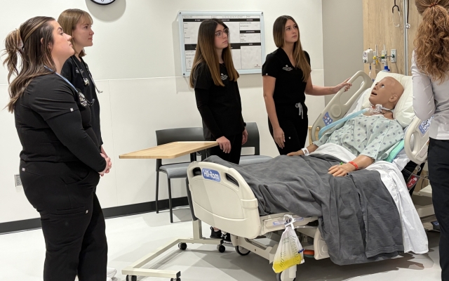 Nursing students standing around a sample patient