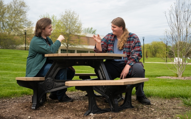 two students sitting on picnic table