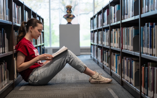 female student in library reading book